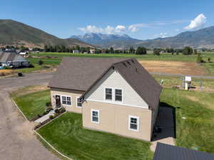View of property exterior featuring stucco siding, a lawn, a mountain view, and a view of rural / pastoral area