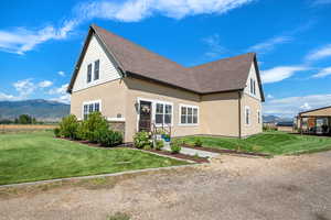 Rear view of house with a mountain view, roof with shingles, a lawn, and stucco siding