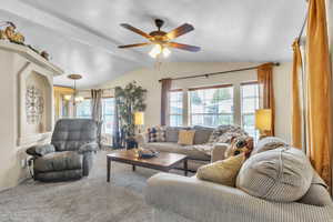 Living room with plenty of natural light, carpet flooring, and a ceiling fan