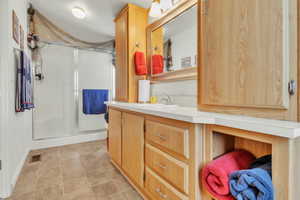 Bathroom with a stall shower, vanity, and light tile patterned floors