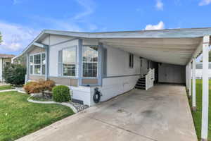 View of front of home with a front yard, concrete driveway, and a carport