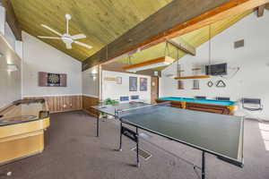 Recreation room with high vaulted ceiling, dark colored carpet, billiards table, a wooden ceiling with exposed beams, and a ceiling fan