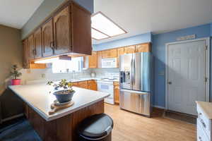 Kitchen with a peninsula, light countertops, light LVP flooring, and a kitchen bar