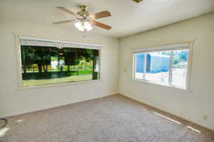 Carpeted spare room with baseboards and ceiling fan