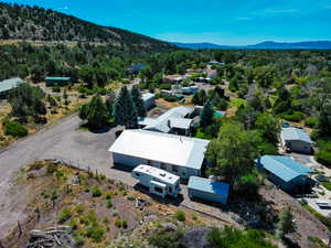 Aerial view of property and surrounding area featuring a forest and a mountainous background