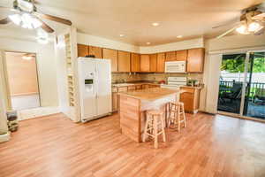 Kitchen with ceiling fan, white appliances, tasteful backsplash, a breakfast bar area, and recessed lighting