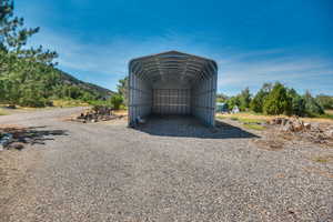 View of outbuilding with a detached carport and gravel driveway