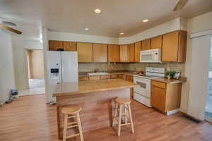 Kitchen with a ceiling fan, white appliances, backsplash, a kitchen breakfast bar, and recessed lighting