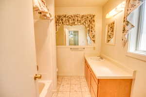 Bathroom featuring light tile patterned floors, vanity, and bathing tub / shower combination