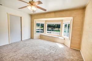 Unfurnished bedroom with multiple windows, carpet flooring, and a ceiling fan
