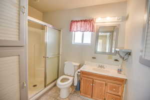 Full bath featuring a shower stall, vanity, and light tile patterned floors
