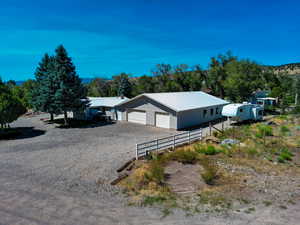 View of front facade with a garage, a metal roof, and driveway