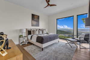 Bedroom with a mountain view, wood finished floors, and a ceiling fan
