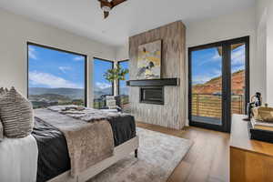 Bedroom featuring a mountain view, access to exterior, light wood-style floors, and a large fireplace