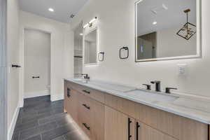 Bathroom with double vanity, recessed lighting, and dark tile patterned floors