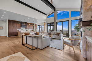 Living room featuring beam ceiling, light wood finished floors, high vaulted ceiling, a large fireplace, and recessed lighting