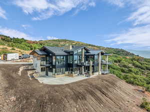 Rear view of property featuring stone siding, a balcony, a mountain view, a chimney, and board and batten siding