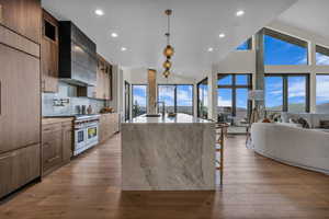Kitchen with glass insert cabinets, light wood-style floors, high quality appliances, light stone countertops, and recessed lighting