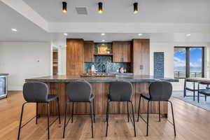 Kitchen with dark countertops, tasteful backsplash, light wood-style floors, recessed lighting, and brown cabinets