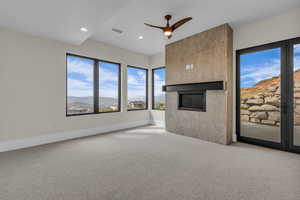 Unfurnished living room featuring a mountain view, carpet flooring, a ceiling fan, a fireplace, and recessed lighting