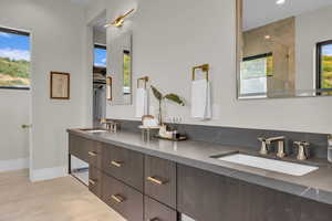 Bathroom featuring double vanity, a shower with shower door, a closet, and recessed lighting