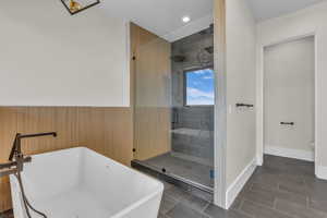 Bathroom with a freestanding tub, a shower stall, recessed lighting, and a wainscoted wall