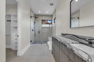 Full bath featuring walk in shower, double vanity, recessed lighting, and a walk in closet