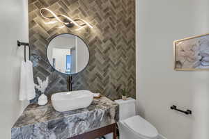 Half bath with tile walls, vanity, and tasteful backsplash