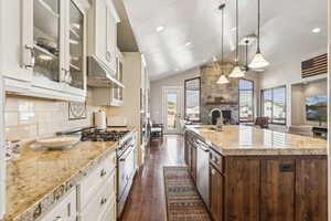 Kitchen featuring glass insert cabinets, white cabinetry, decorative light fixtures, high vaulted ceiling, and recessed lighting