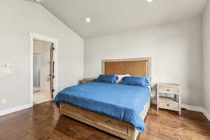 Bedroom with hardwood / wood-style floors, recessed lighting, vaulted ceiling, and ensuite bath