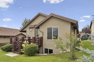 Rear view of house featuring a yard, stucco siding, and a wooden deck