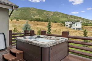 Wooden terrace with a hot tub, a mountain view, and a view of rural / pastoral area