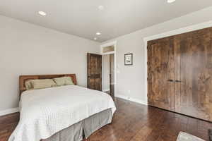 Bedroom with dark wood finished floors, recessed lighting, and a closet