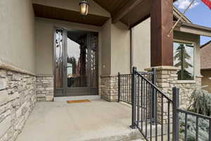 Doorway to property featuring stone siding, stucco siding, and a patio area