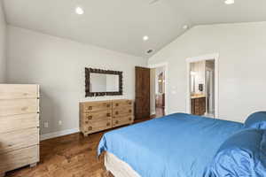 Bedroom featuring wood finished floors, vaulted ceiling, recessed lighting, and connected bathroom