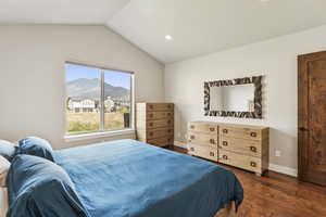 Bedroom featuring dark wood-style floors, lofted ceiling, recessed lighting, and a mountain view
