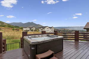 Wooden terrace featuring a mountain view, a hot tub, and a residential view
