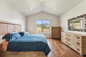 Bedroom with multiple windows, lofted ceiling, hardwood / wood-style flooring, recessed lighting, and a mountain view