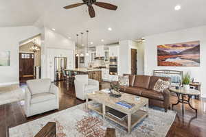 Living room featuring dark wood finished floors, a chandelier, recessed lighting, a ceiling fan, and high vaulted ceiling