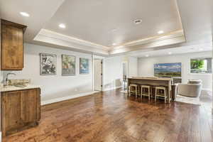 Dining room featuring a raised ceiling, dark wood-type flooring, recessed lighting, and crown molding