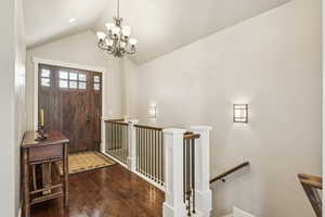 Entryway featuring a chandelier, lofted ceiling, and dark wood-style flooring