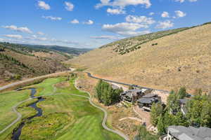 Aerial view of property's location with a golf club and a water and mountain view