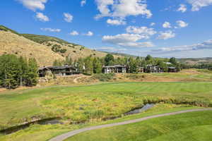 View of mountain backdrop with a golf course and a nearby body of water