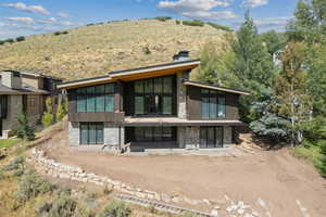 Rear view of property featuring stone siding, a patio area, a chimney, and a mountain view
