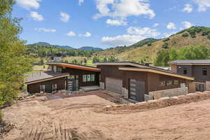 View of front of home with stone siding, driveway, a mountain view, and a garage