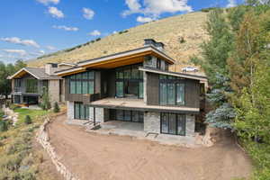 Rear view of property with stone siding, a chimney, and a patio area