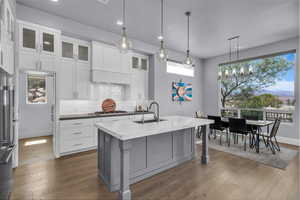 Kitchen featuring decorative light fixtures, gray cabinetry, glass insert cabinets, backsplash, and recessed lighting