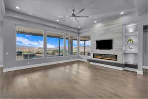 Unfurnished living room featuring built in features, wood finished floors, a fireplace, ceiling fan, and recessed lighting
