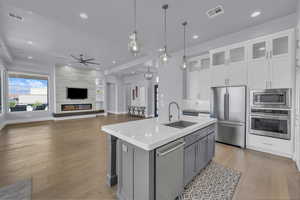 Kitchen with white cabinets, gray cabinets, stainless steel appliances, decorative light fixtures, and light wood-style flooring