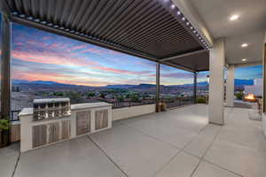 Patio terrace at dusk with a patio area, area for grilling, a mountain view, and a fire pit
